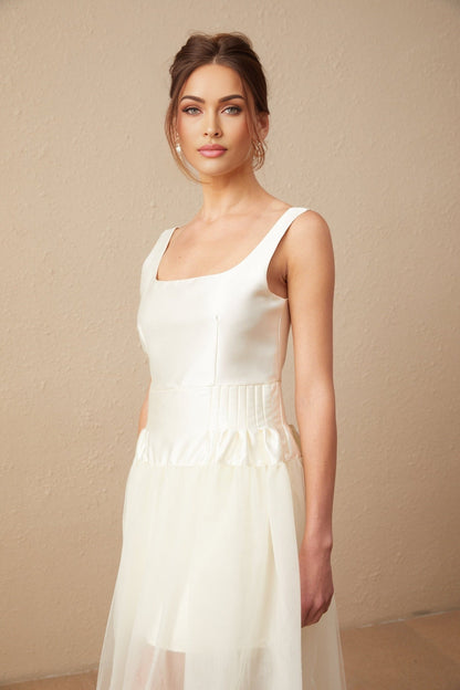 A white satin maxi dress with tulle panels named Lucie featuring a long flowing skirt and elegant design