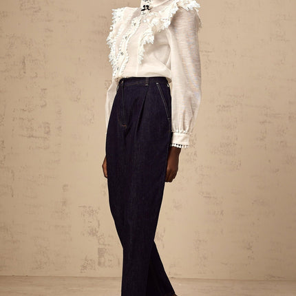 A white semi sheer shirt with delicate lace trim details named Capucine hanging on display