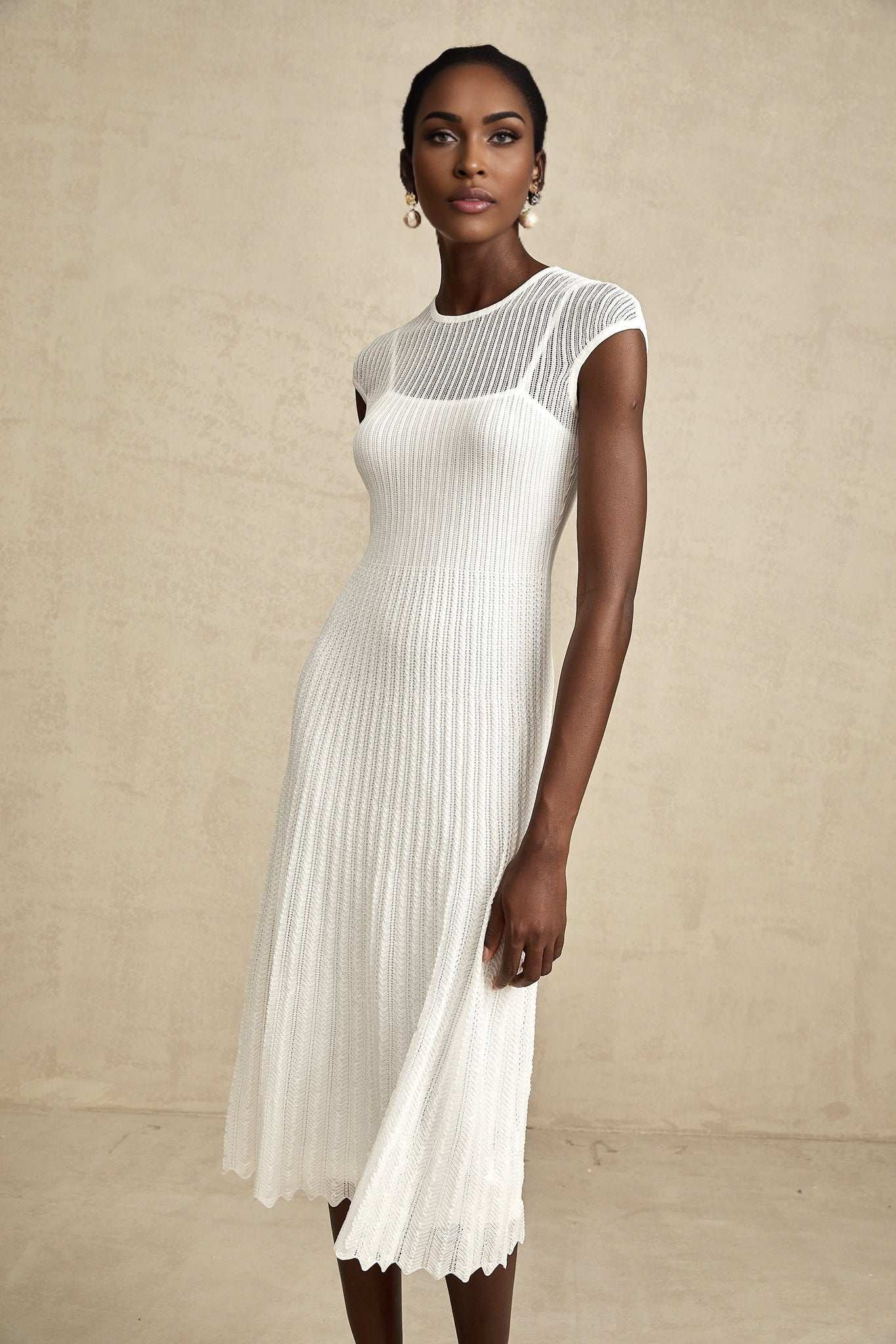 A white semisheer midi dress with scalloped hem details and delicate lace patterns named Liane