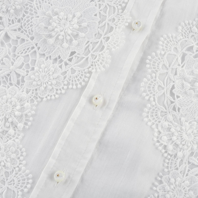A white shirt with delicate lace embroidery and strategic cut out details featuring long sleeves and a feminine silhouette