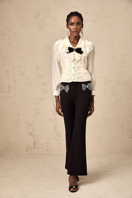 A white shirt with lace trim and a decorative bow knot detail on the front