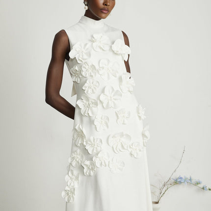 A white sleeveless maxi dress with a bow and artificial flower embellishments named Magali