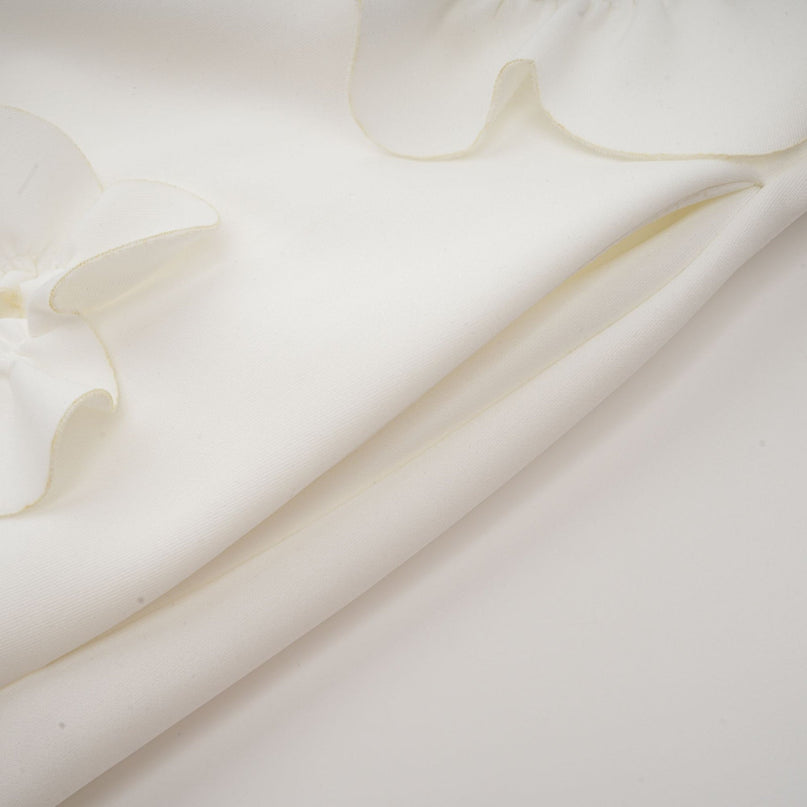 A white sleeveless maxi dress with a bow and decorative artificial flowers named Magali