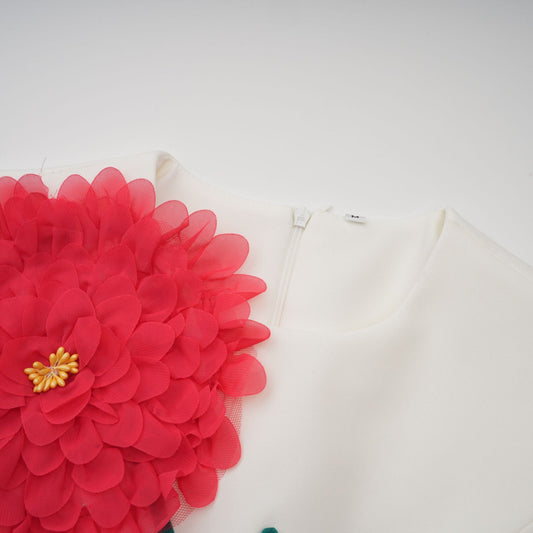A white sleeveless midi dress with 3d floral petal details worn by a model named Veronique