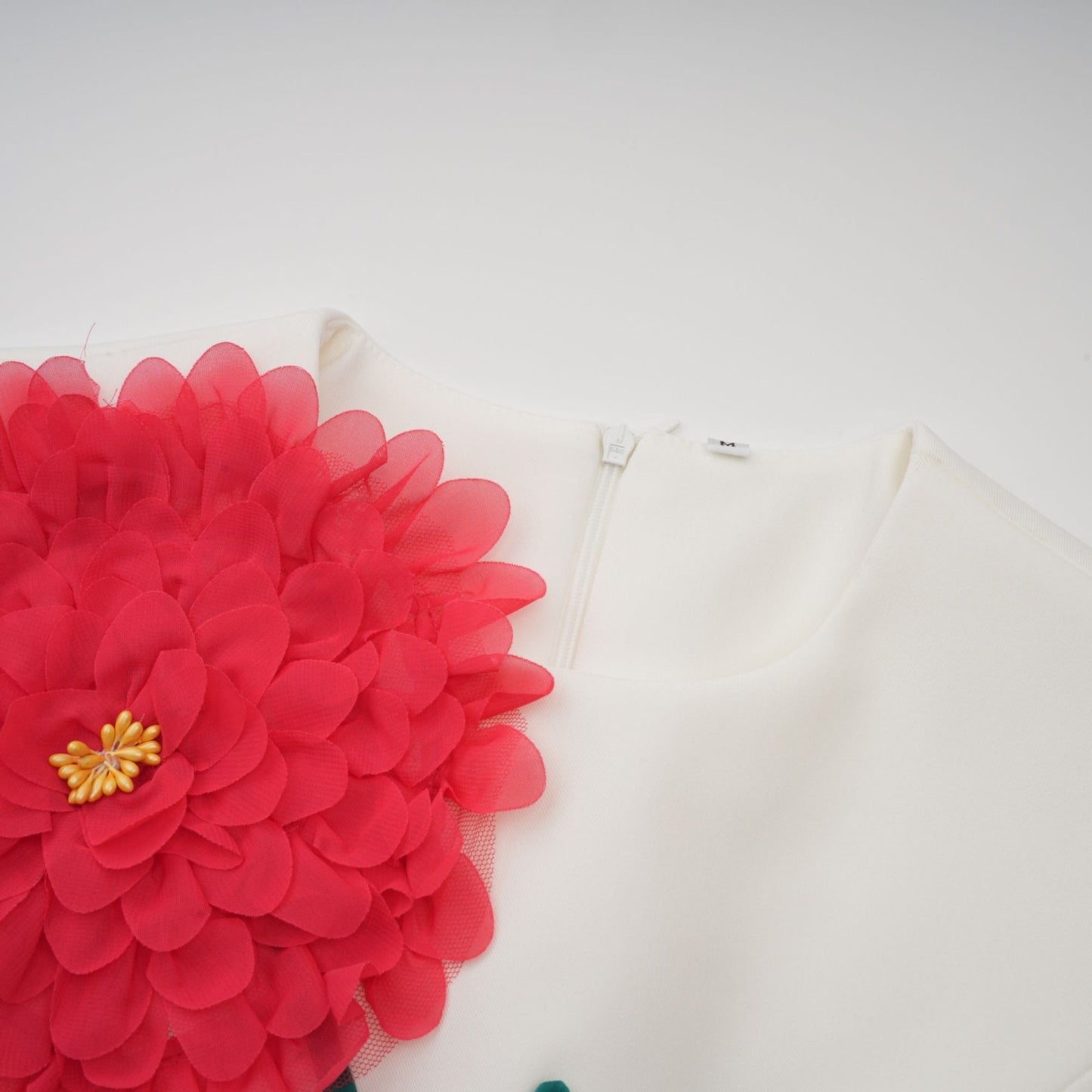 A white sleeveless midi dress with 3d floral petal details worn by a model named Veronique