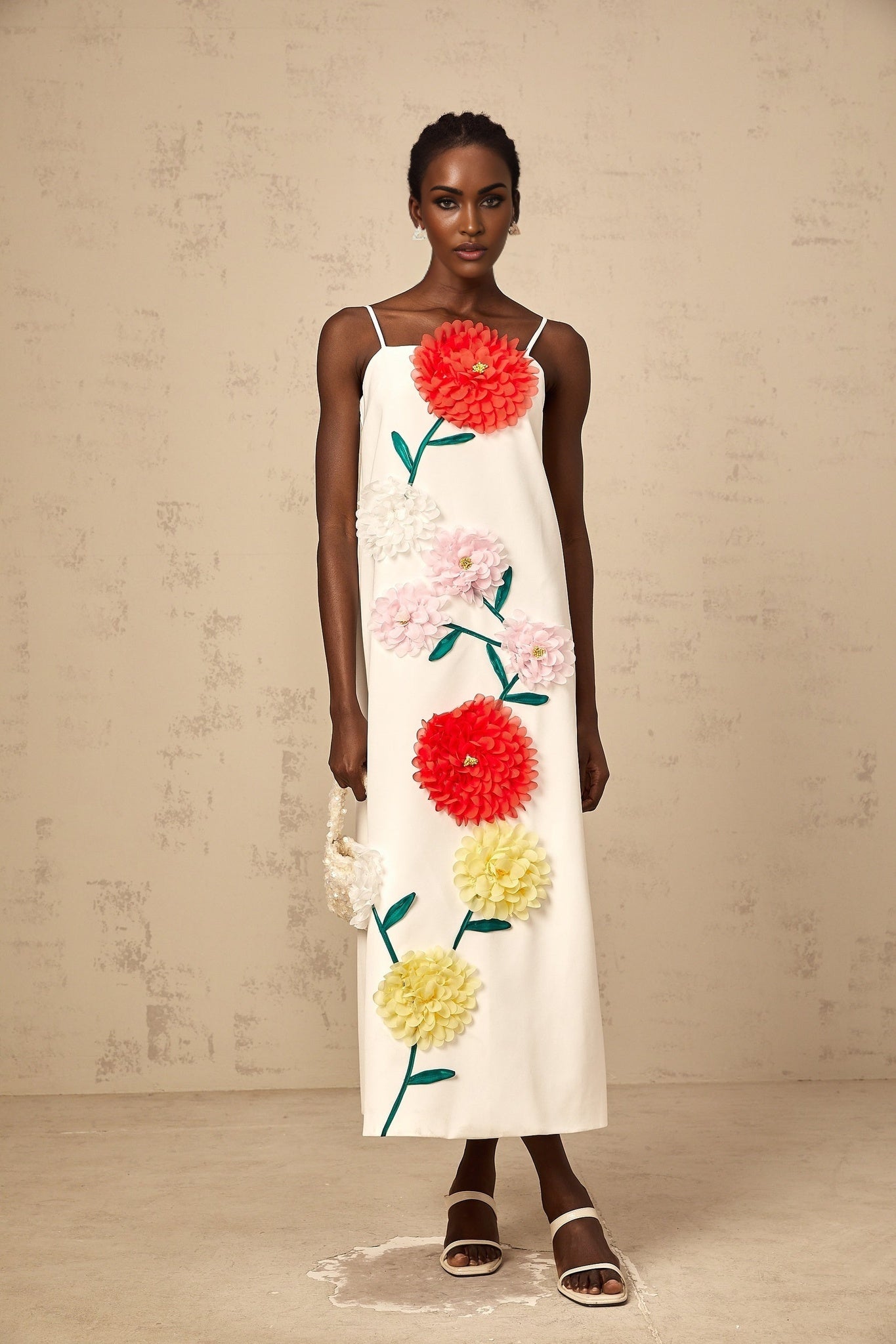 A white sleeveless midi dress with 3D petal details on the bodice featuring a fitted waist and flared skirt