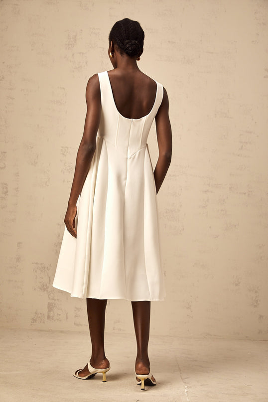 A white sleeveless midi dress with a full skirt worn by a model named Yolanda