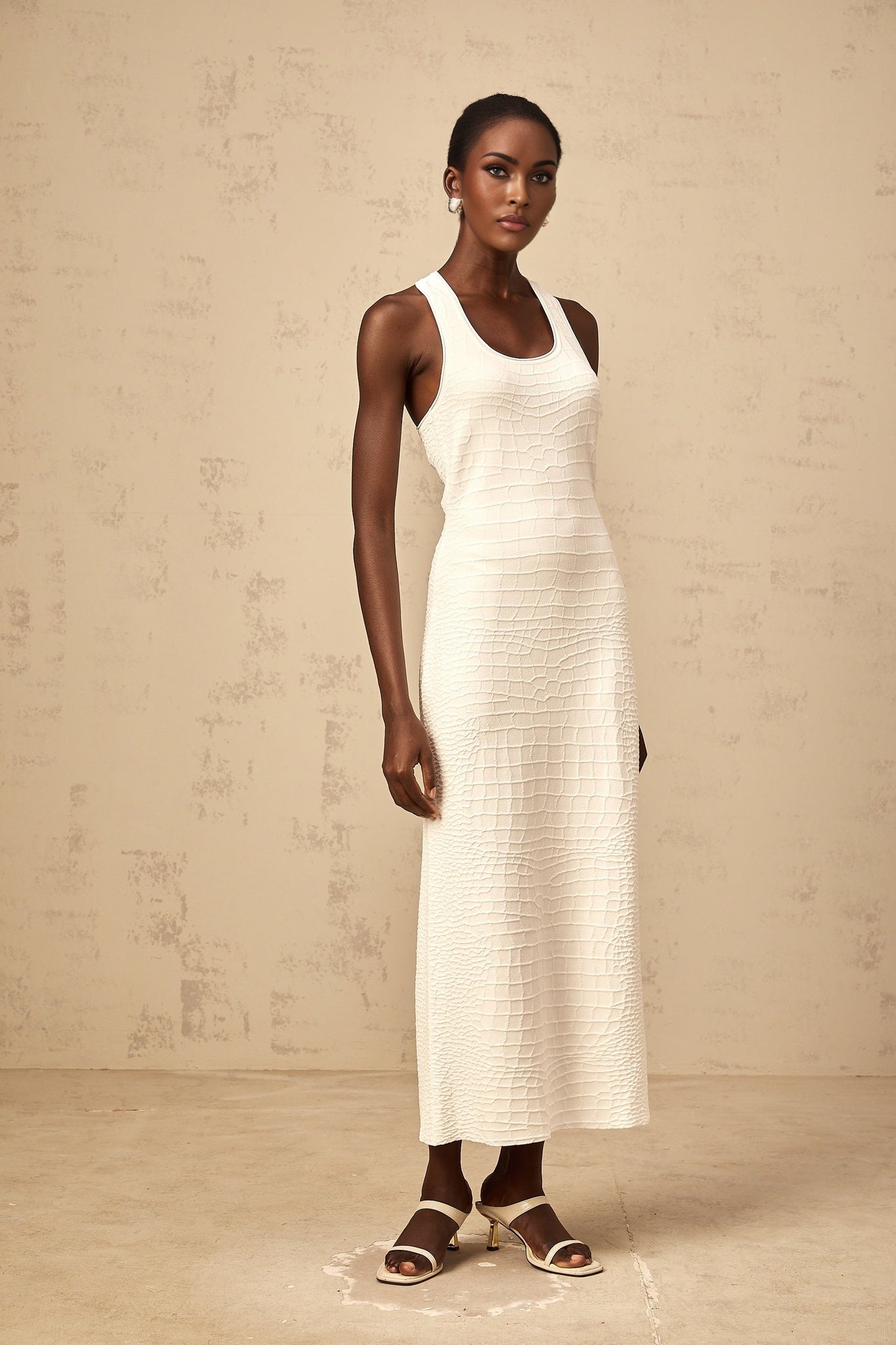 A white sleeveless midi dress with a textured jacquard pattern featuring a tank top style bodice and a fitted silhouette