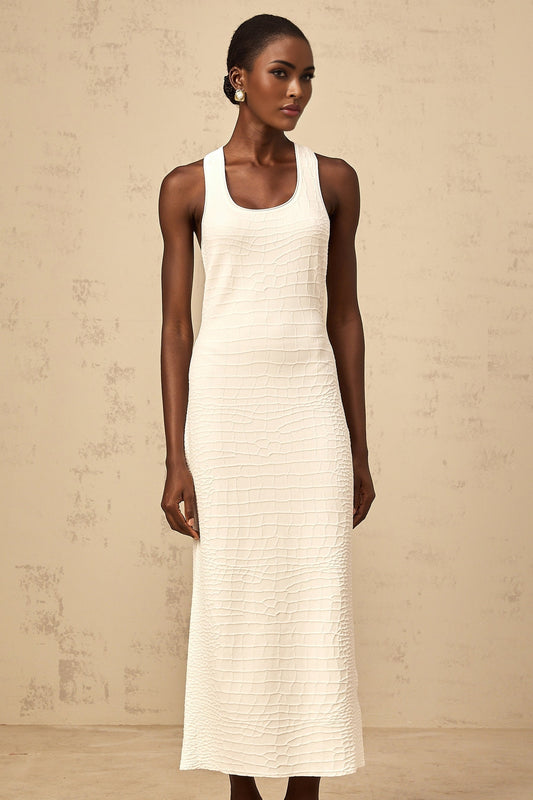 A white sleeveless midi dress with a textured jacquard pattern worn by a woman standing in a neutral setting