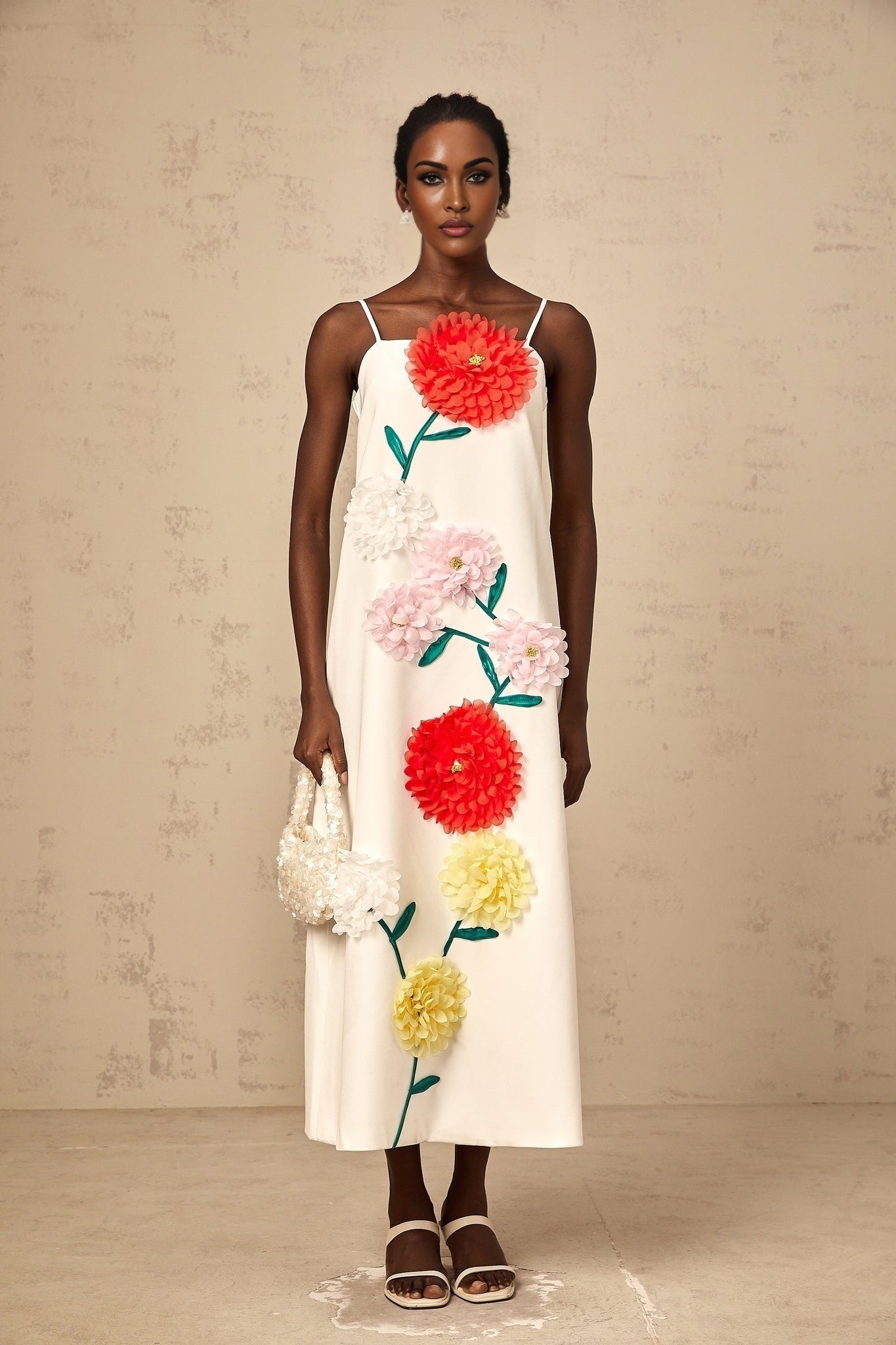 A white sleeveless midi dress with three dimensional petal details covering the bodice