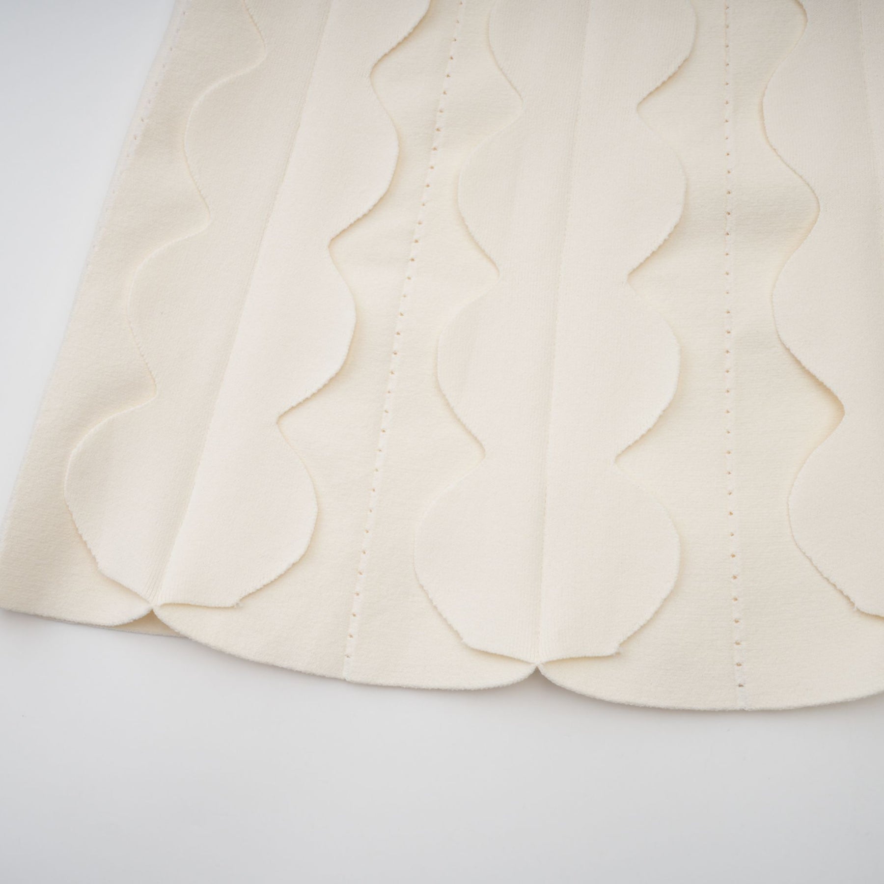 A white sleeveless mini dress with wavy details called Axelle