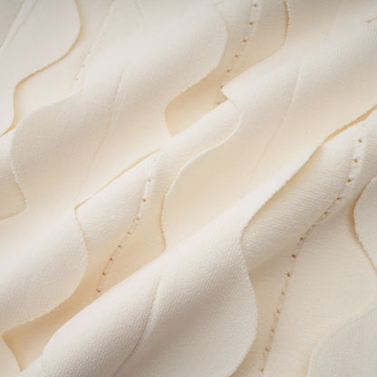 A white sleeveless mini dress with wavy details on a female model standing against a plain background