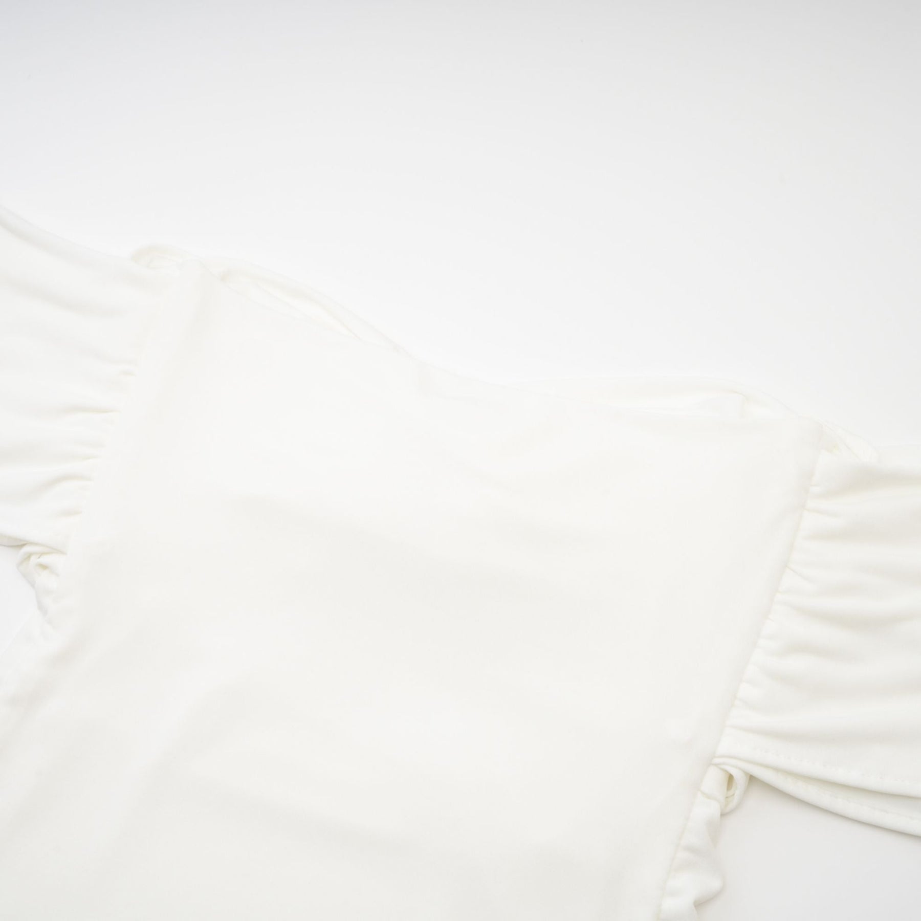 A white sleeveless top with gathered details featuring a feminine design and relaxed fit