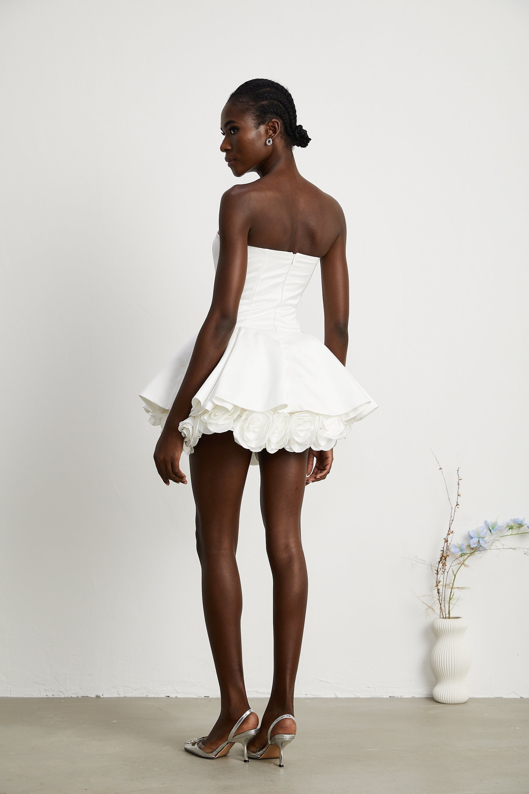 A white strapless mini dress with a corsetstyle bodice adorned with floral petal details named Lucie