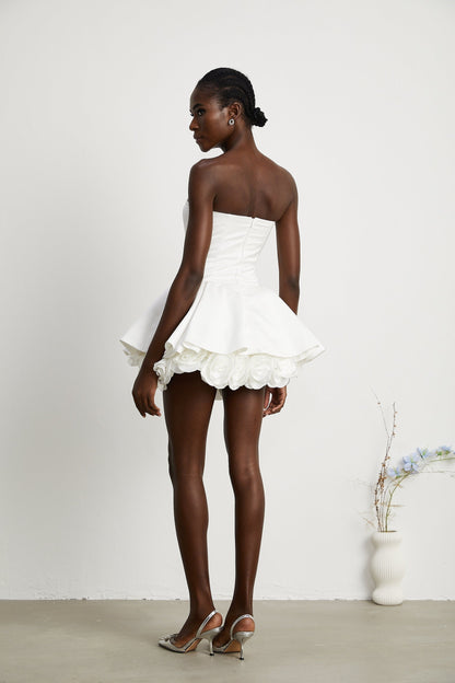 A white strapless mini dress with a corsetstyle bodice adorned with floral petal details named Lucie