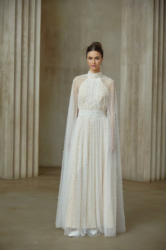 A white tulle maxi dress with cape design and embellishments featuring a flowing silhouette and delicate details
