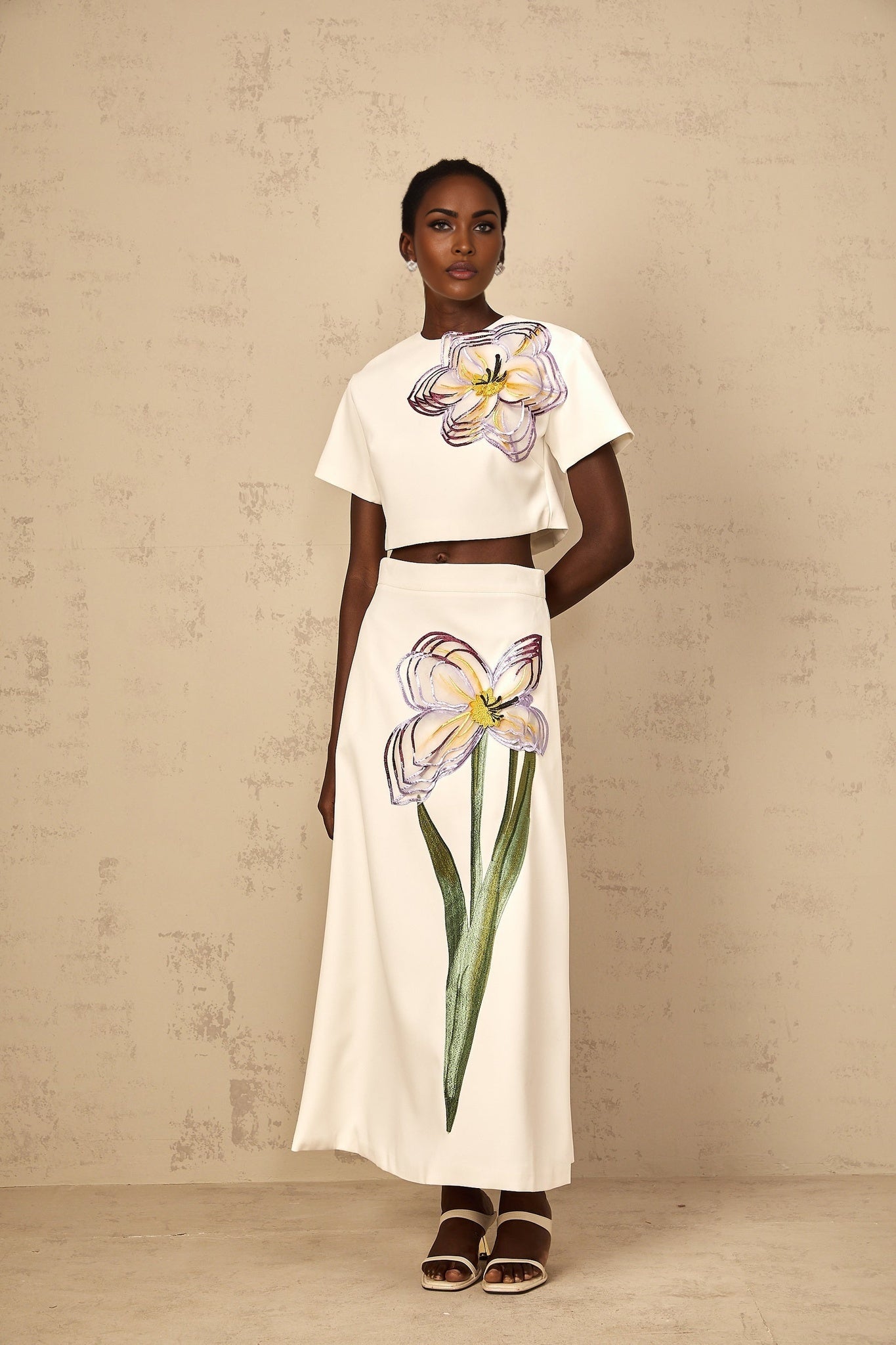 A white twopiece outfit for women featuring sequin floral embroidery details on both the top and bottom matching set