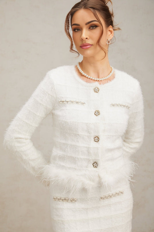 A white waffle knit matching set featuring a cardigan and skirt with feather details