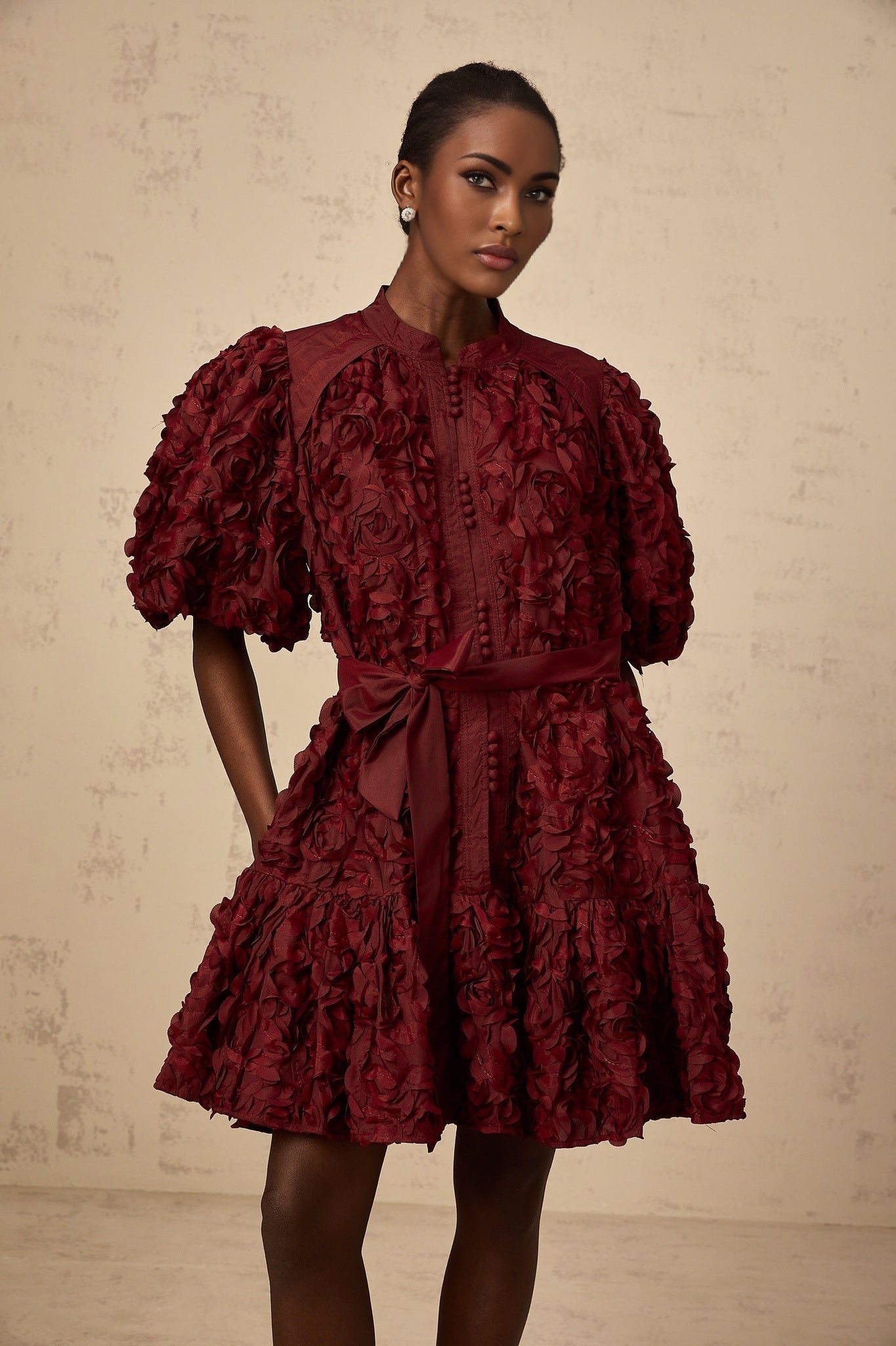 A winered mini dress with puffed sleeves and a 3D petal texture covering the entire garment named Segolene
