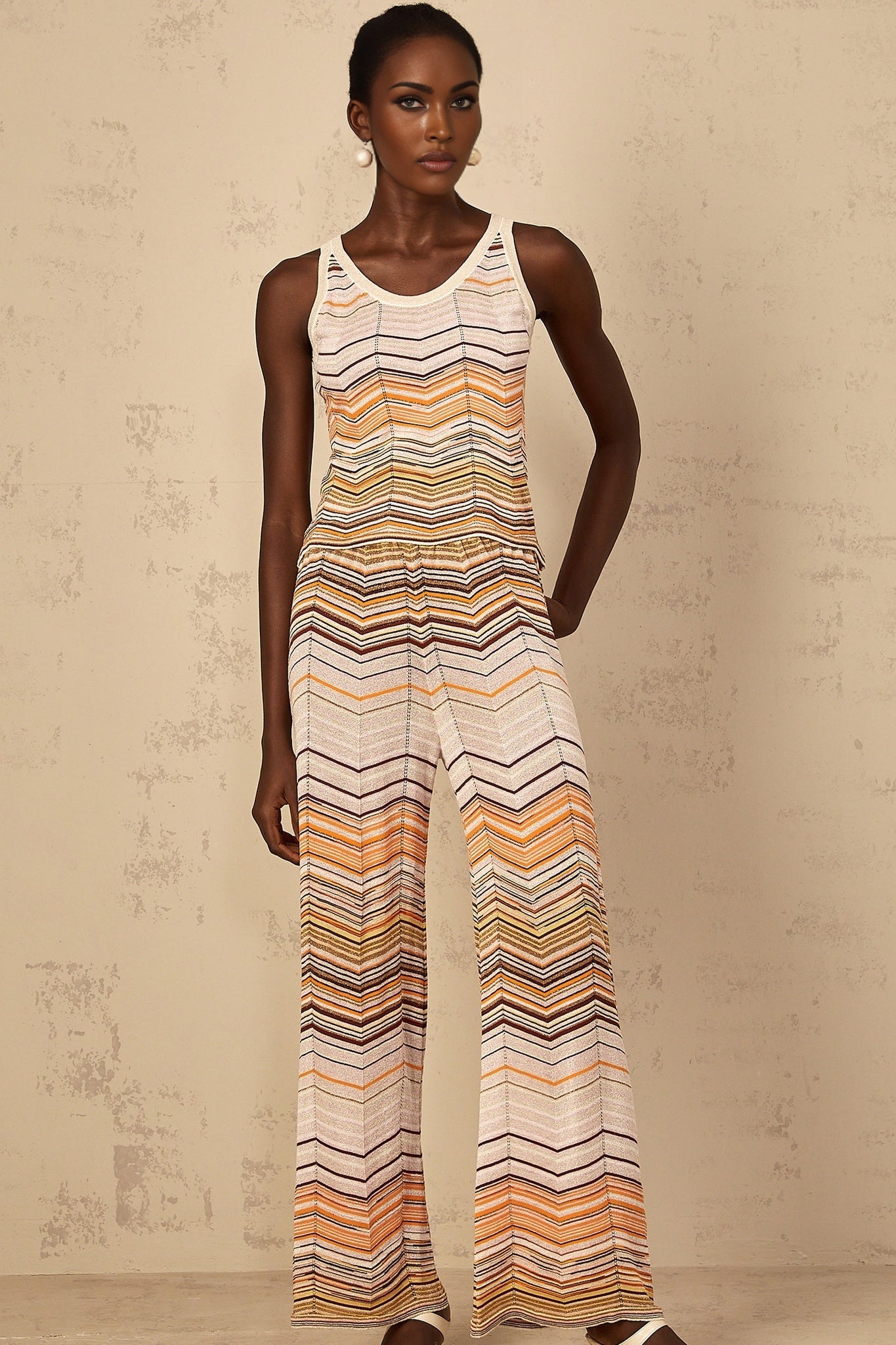 A woman wearing a beige and cream striped knit matching set consisting of a long sleeve top and wide leg pants from Chloe