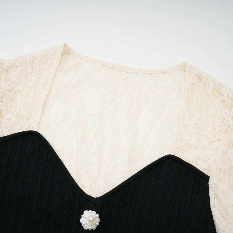 A woman wearing a beige knit midi dress with delicate lace trim along the neckline and sleeves standing in a neutral background