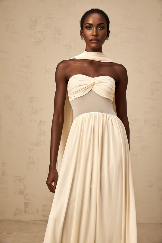 A woman wearing a beige midi dress with a scarflike mesh design featuring neutral tones and a flowing silhouette