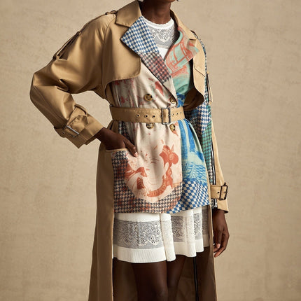 A woman wearing a belted trench coat with contrasting colors and a printed design The coat features a classic trench style with lapels and a tie belt at the waist