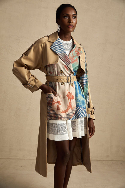 A woman wearing a belted trench coat with contrasting colors and a printed design The coat features a classic trench style with lapels and a tie belt at the waist