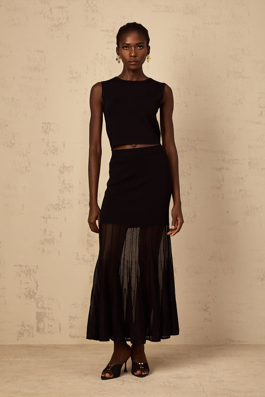 A woman wearing a black fine knit matching set with panelled details consisting of a top and bottoms