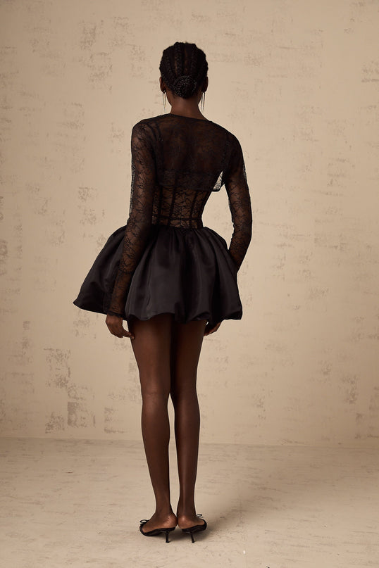 A woman wearing a black floral lace vest over a matching sleeveless dress the set features delicate lace patterns throughout