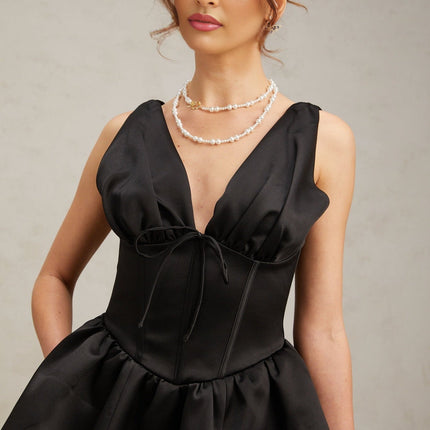 A woman wearing a black mini dress with a Vneckline and flared skirt