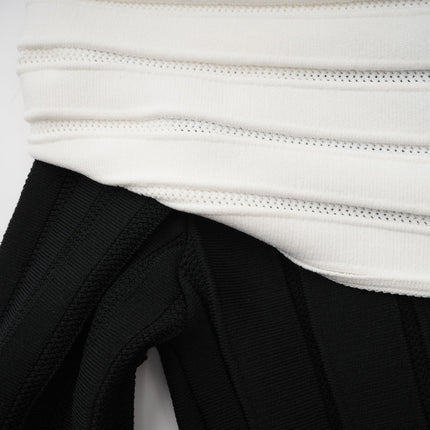 A woman wearing a black offshoulder mini dress with a bow detail and knit fabric