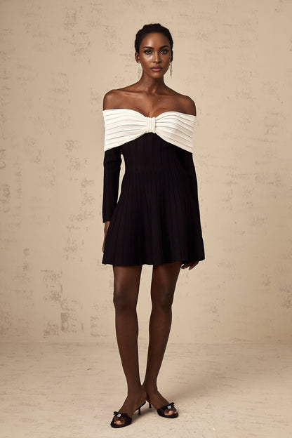 A woman wearing a black offshoulder mini dress with a bow detail and knit fabric