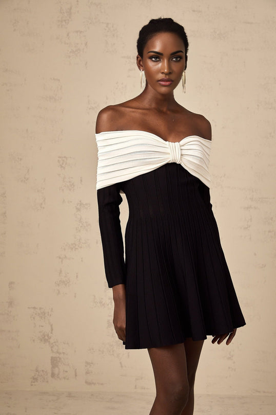 A woman wearing a black offshoulder mini dress with a bow detail and knit texture
