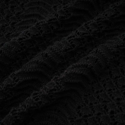 A woman wearing a black sequined matching set consisting of a crochet knit cardigan and skirt