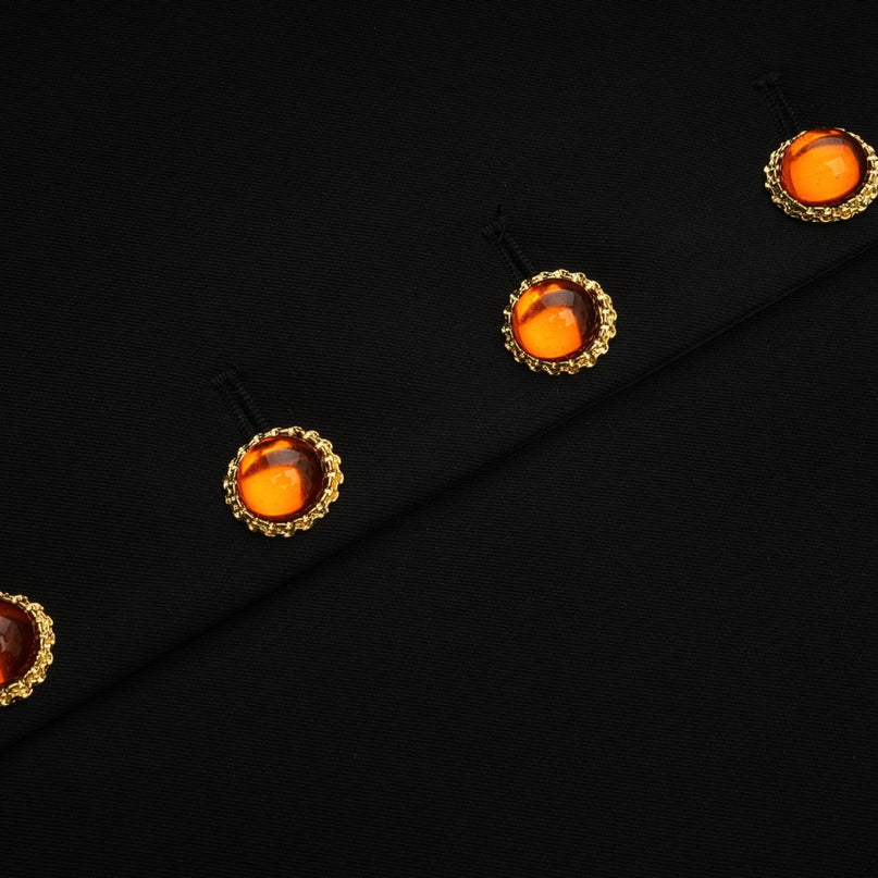 A woman wearing a black singlebreasted blazer dress with a fitted silhouette and a tailored collar standing against a plain background