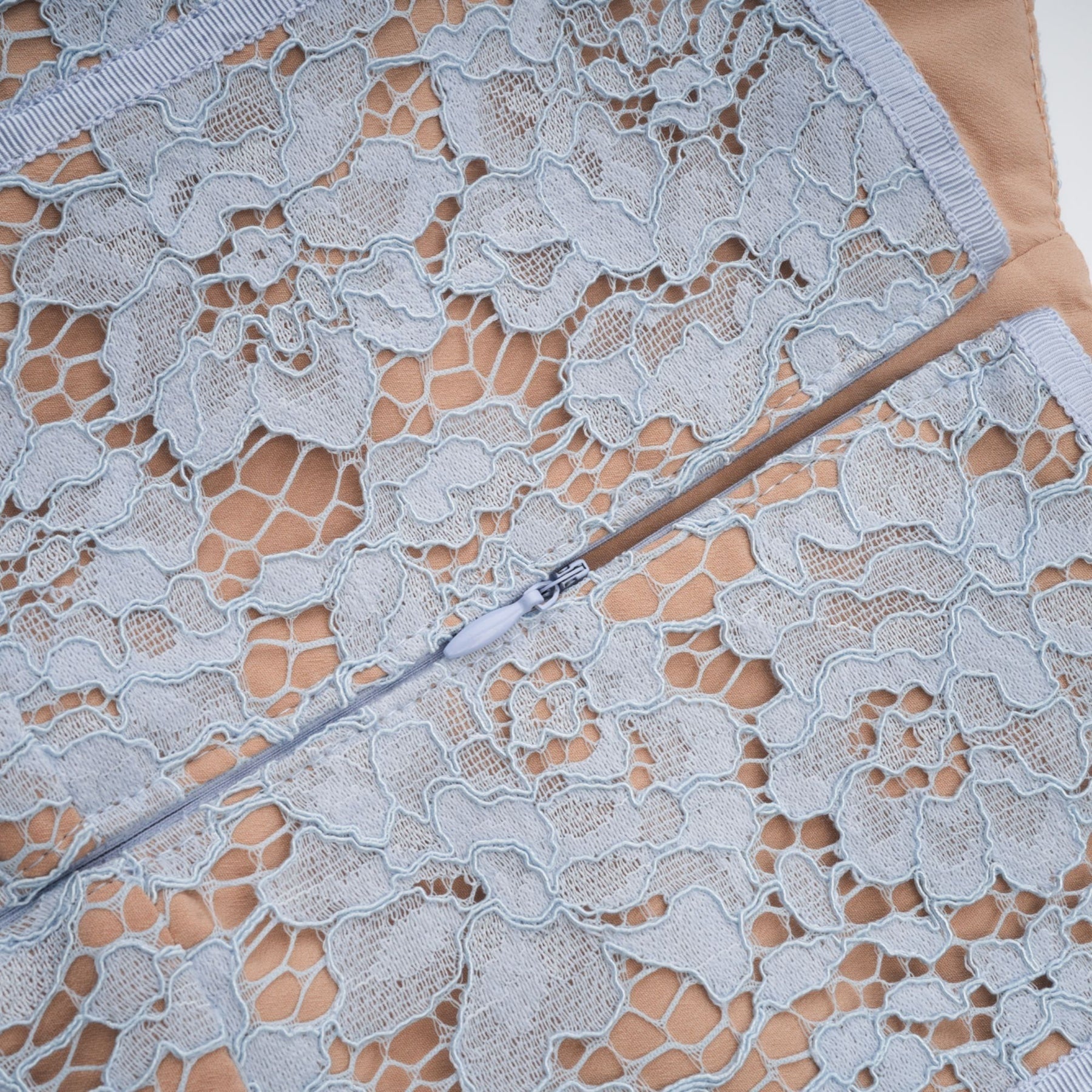 A woman wearing a blue midi dress with floral lace pattern and boned bodice