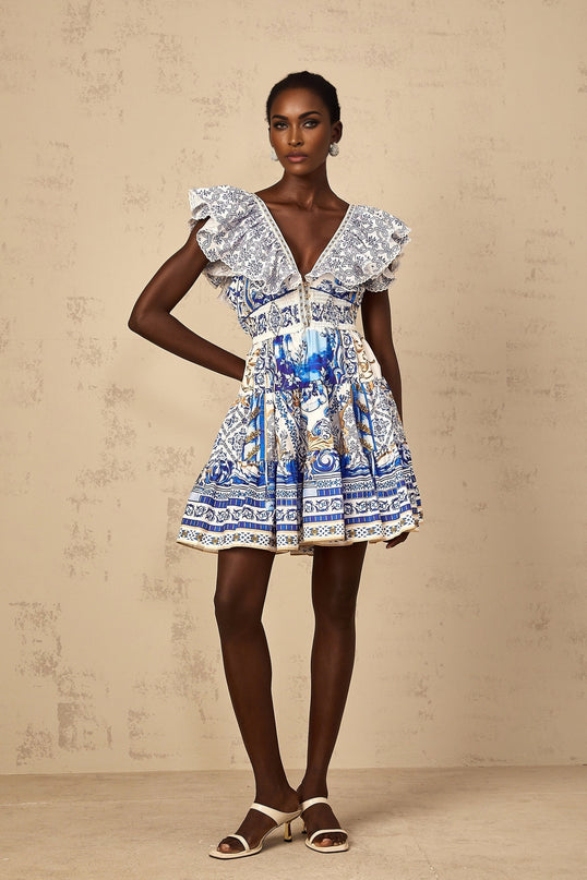 A woman wearing a blue mini dress with baroque print pattern and tiered skirt design