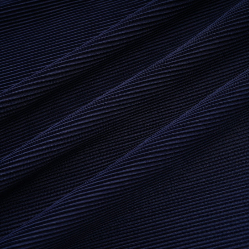 A woman wearing a blue patterned cape and matching skirt set Debbie model The cape is creased and flows over the shoulders The skirt is fitted and falls below the knee Both pieces feature a repeating print pattern in shades of blue