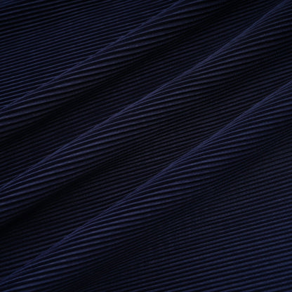 A woman wearing a blue patterned cape and matching skirt set Debbie model The cape is creased and flows over the shoulders The skirt is fitted and falls below the knee Both pieces feature a repeating print pattern in shades of blue