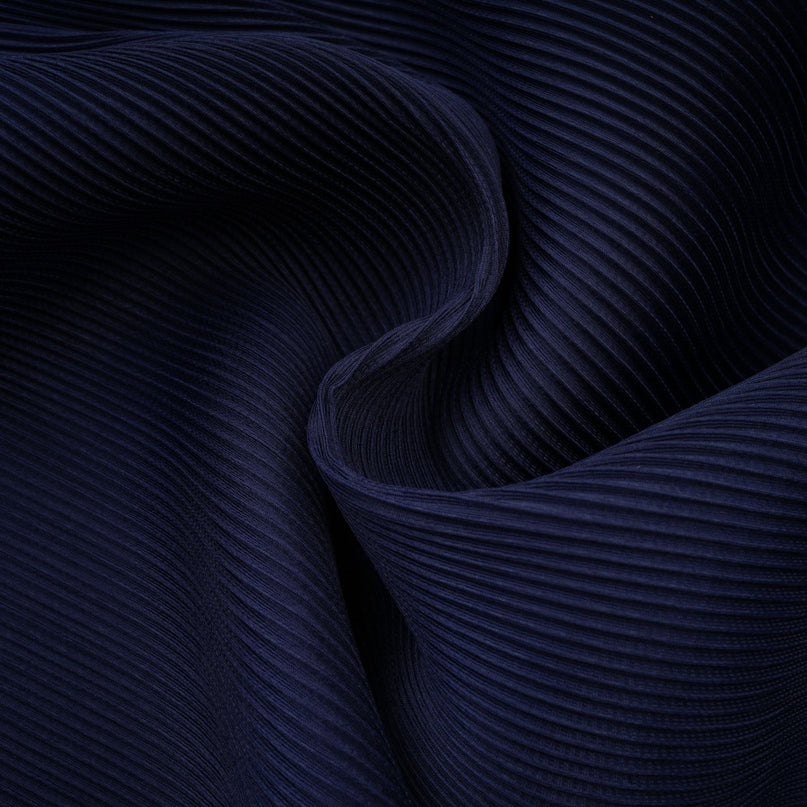 A woman wearing a blue patterned cape and matching skirt set The cape has a creased texture and the skirt features the same print The outfit is called Debbie and has a coordinated look