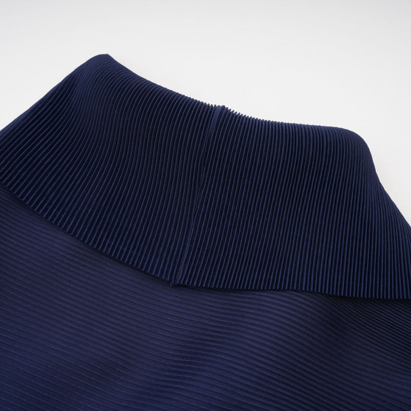 A woman wearing a blue patterned cape and matching skirt set The cape is creased and flows over the shoulders while the skirt falls to mid calf Both pieces feature a bold allover print design in shades of blue