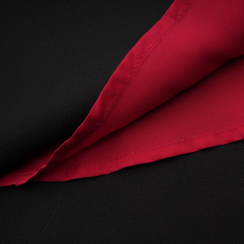 A woman wearing a bright red matching set consisting of a pleated blouse and skirt The blouse has long sleeves and a high neckline while the skirt falls to midi length with pleats throughout The outfit is styled on a model against a plain background