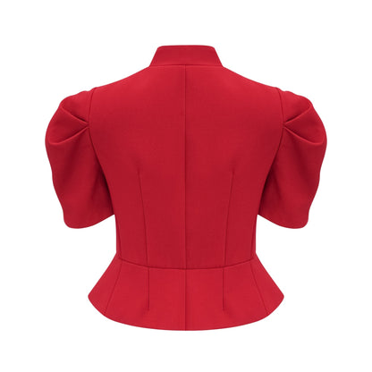 A woman wearing a bright red matching set consisting of a pleated blouse and skirt The blouse has long sleeves and a high neckline while the skirt falls to midi length with pleats throughout The outfit creates a stylish and coordinated look