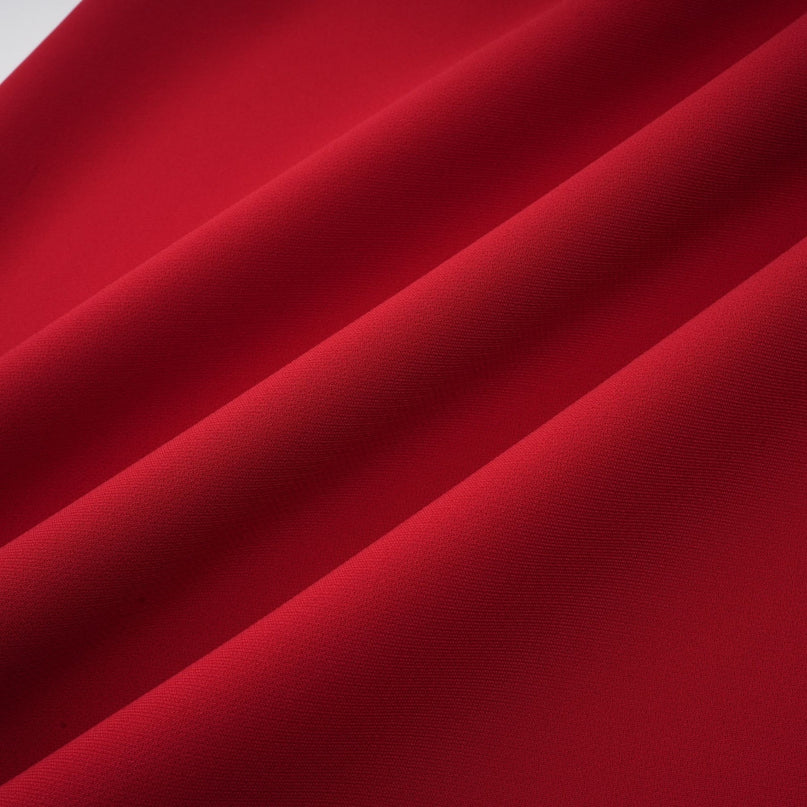 A woman wearing a bright red matching set consisting of a pleated blouse and skirt The blouse has long sleeves and the skirt falls to knee length Both pieces feature pleated details creating a coordinated and elegant look