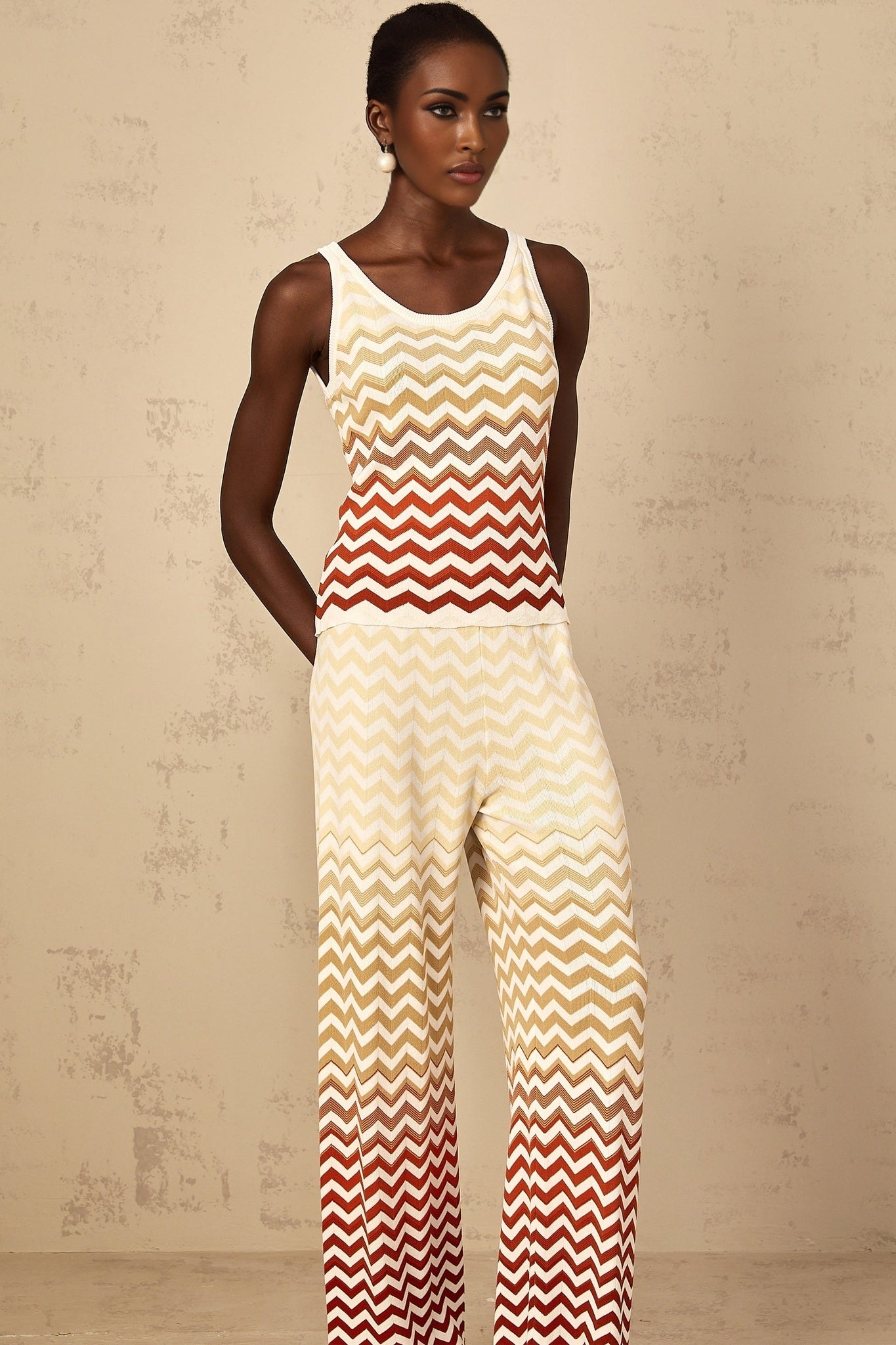 A woman wearing a bright yellow twopiece knit outfit with a zigzag pattern consisting of a cropped top and matching shorts