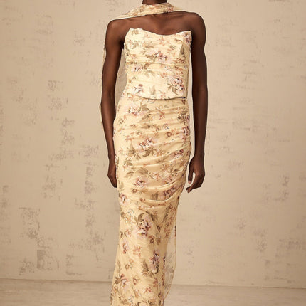 A woman wearing a bright yellow twopiece outfit with a floral print design consisting of a fitted top and matching skirt