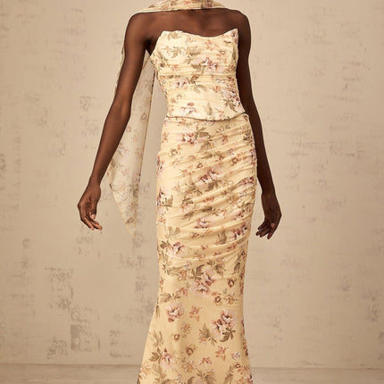 A woman wearing a bright yellow twopiece outfit with a floral print featuring a fitted top and matching skirt