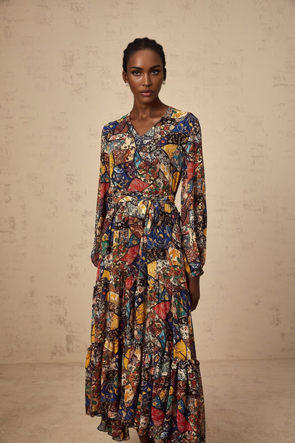 A woman wearing a brown bohemian style midi dress with shirring detail and flowing fabric standing in a casual pose