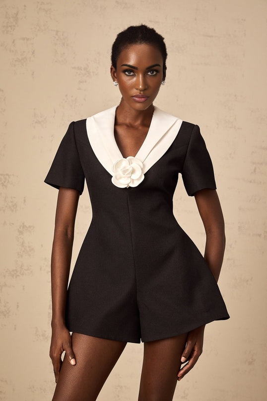 A woman wearing a colorblocked jumpsuit with floral appliques featuring contrasting colors and a fitted silhouette